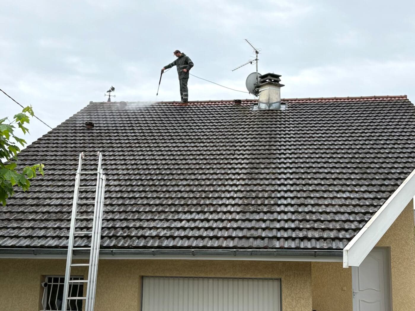 Yohan, de PROUX, nettoyant une toiture en tuile au nettoyeur haute pression dans le Pays de Gex